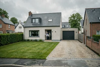 Vue d'ensemble d'une maison individuelle moderne dans un quartier résidentiel de Rennes, avec un couple devant l'entrée tenant des plans architecturaux